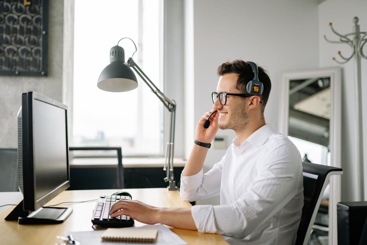 A receptionist wearing a headset, smiling while helping a caller