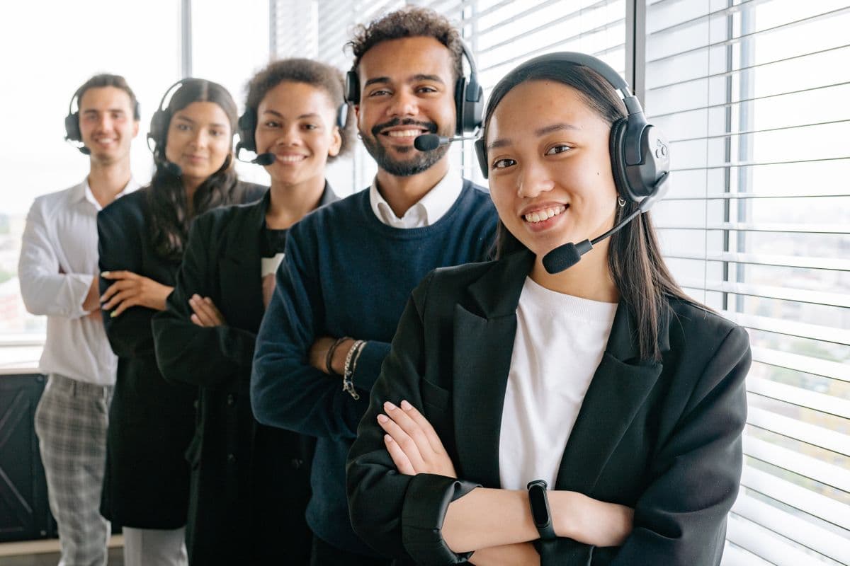 A diverse team of receptionists wearing headsets, smiling together