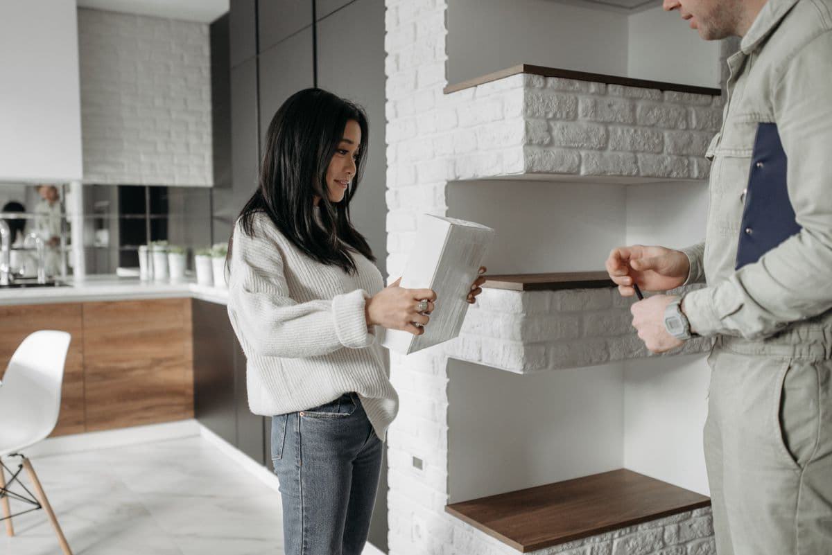 A technician showing a homeowner materials in her kitchen