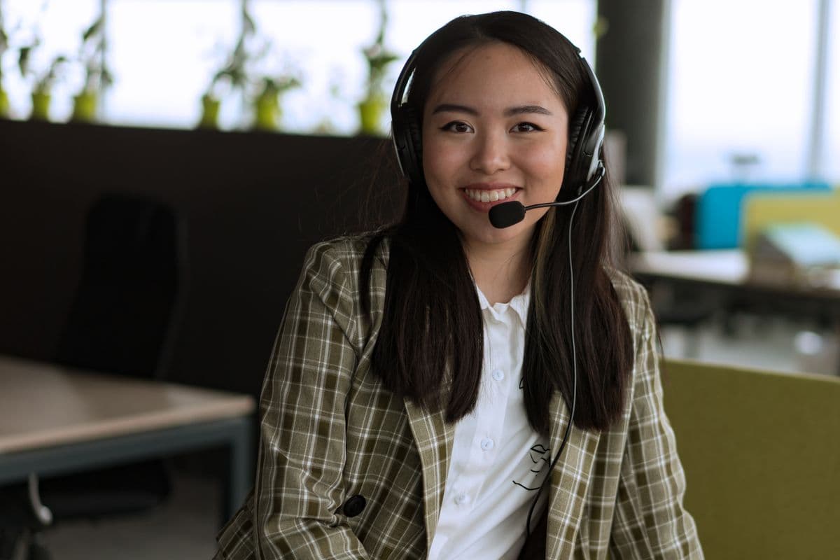 A receptionist wearing a headset, smiling while talking with a caller